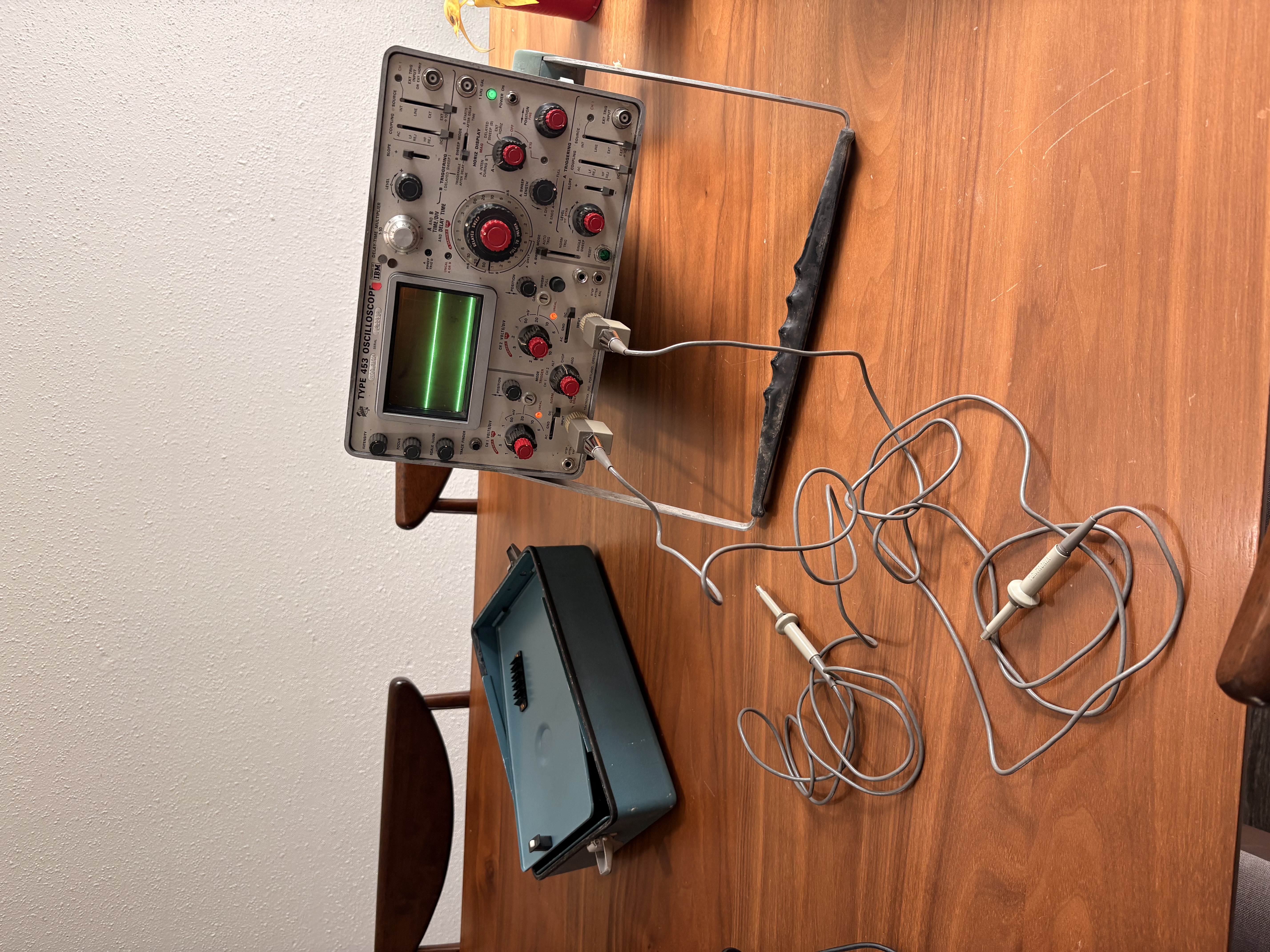 Vintage Tektronix Type 453 oscilloscope on a wooden table displaying green waveforms
